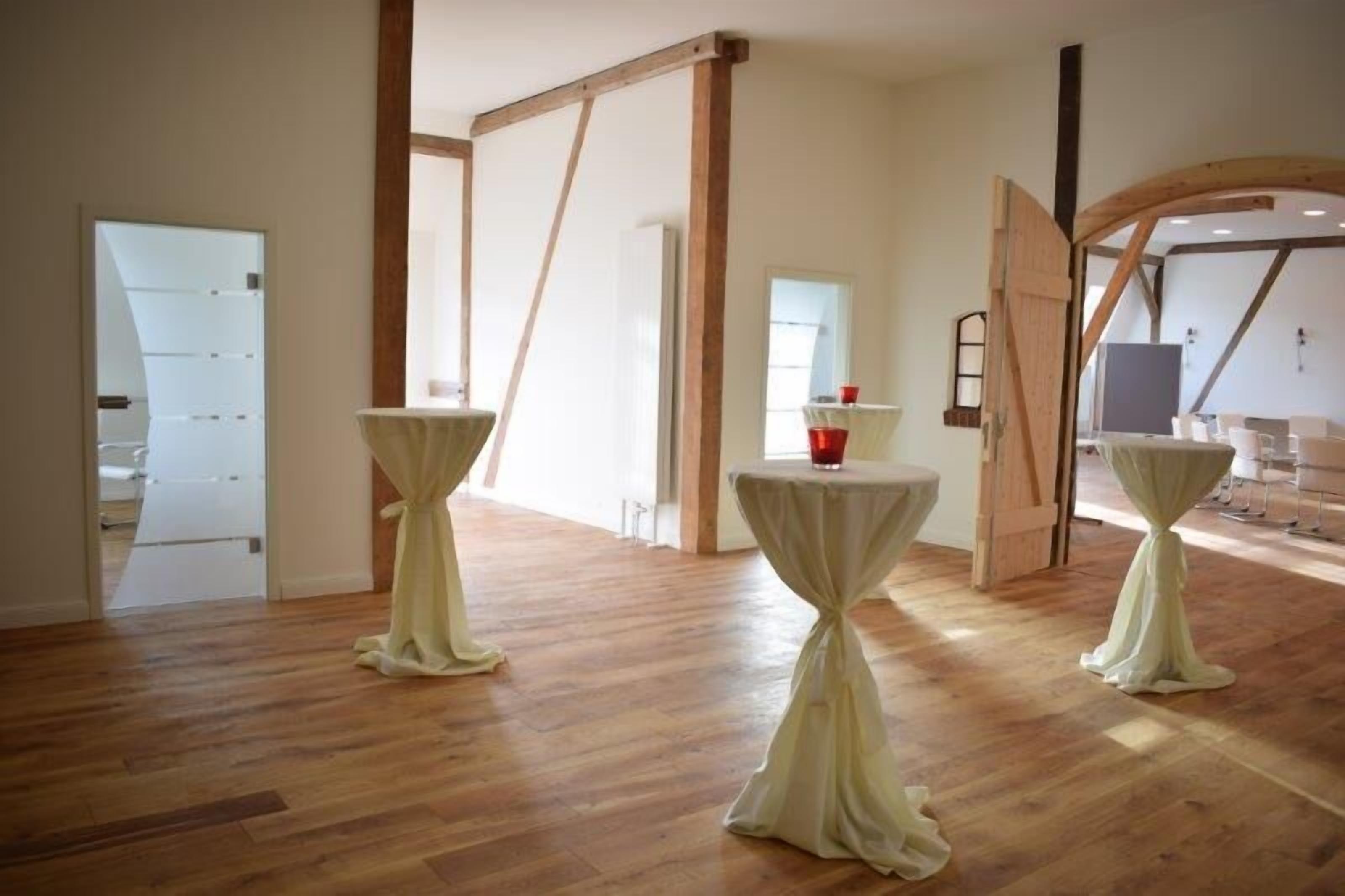 A spacious room with wooden flooring, a large open door, and a small table with a red cup on it.