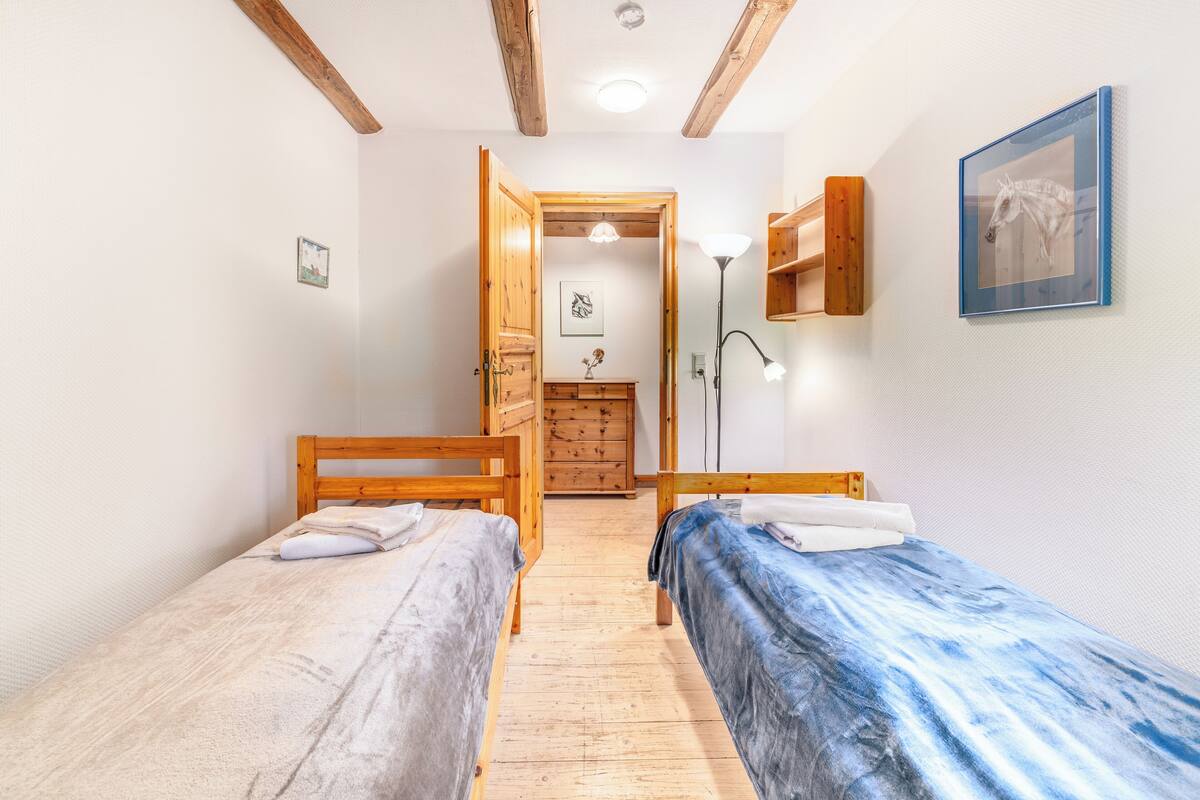 A small, cozy room with two wooden beds, a wooden dresser, and a framed picture on the wall.