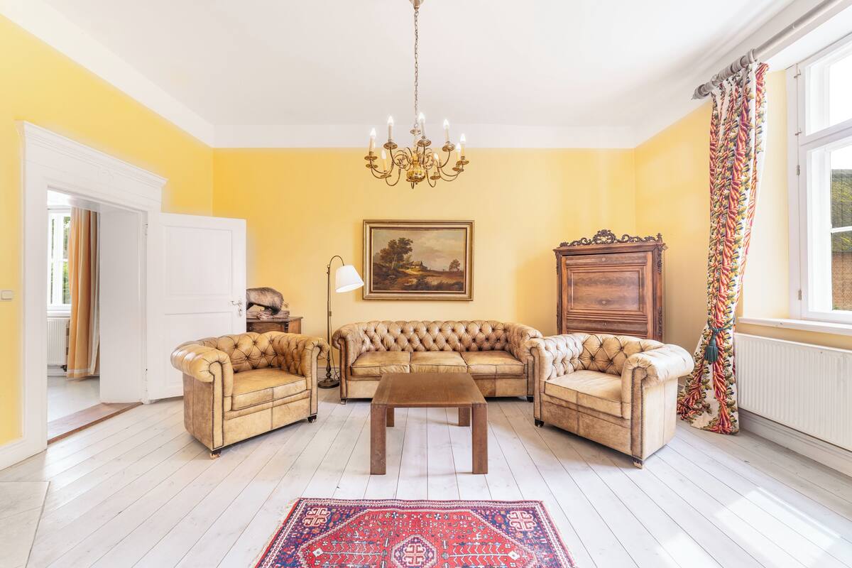 A living room with a beige sofa set, a wooden coffee table, and a chandelier.