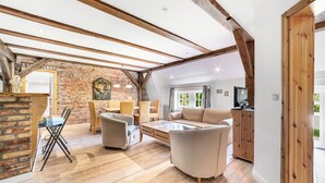 Un loft espacioso con vigas de madera a la vista, pared de ladrillo y un gran ventanal.