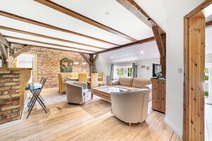 Um amplo loft com vigas de madeira aparentes, parede de tijolos e uma janela grande.