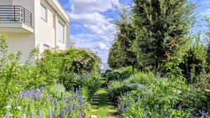 A garden pathway leading to a building with a balcony. - Alternative Relax Rooms by Oikia Vacanze (Scorrano)