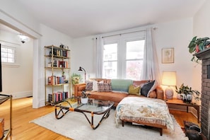 A living room with a sofa, coffee table, bookshelf, and a fireplace. - Century home by river, hot tub & parking (Ottawa)