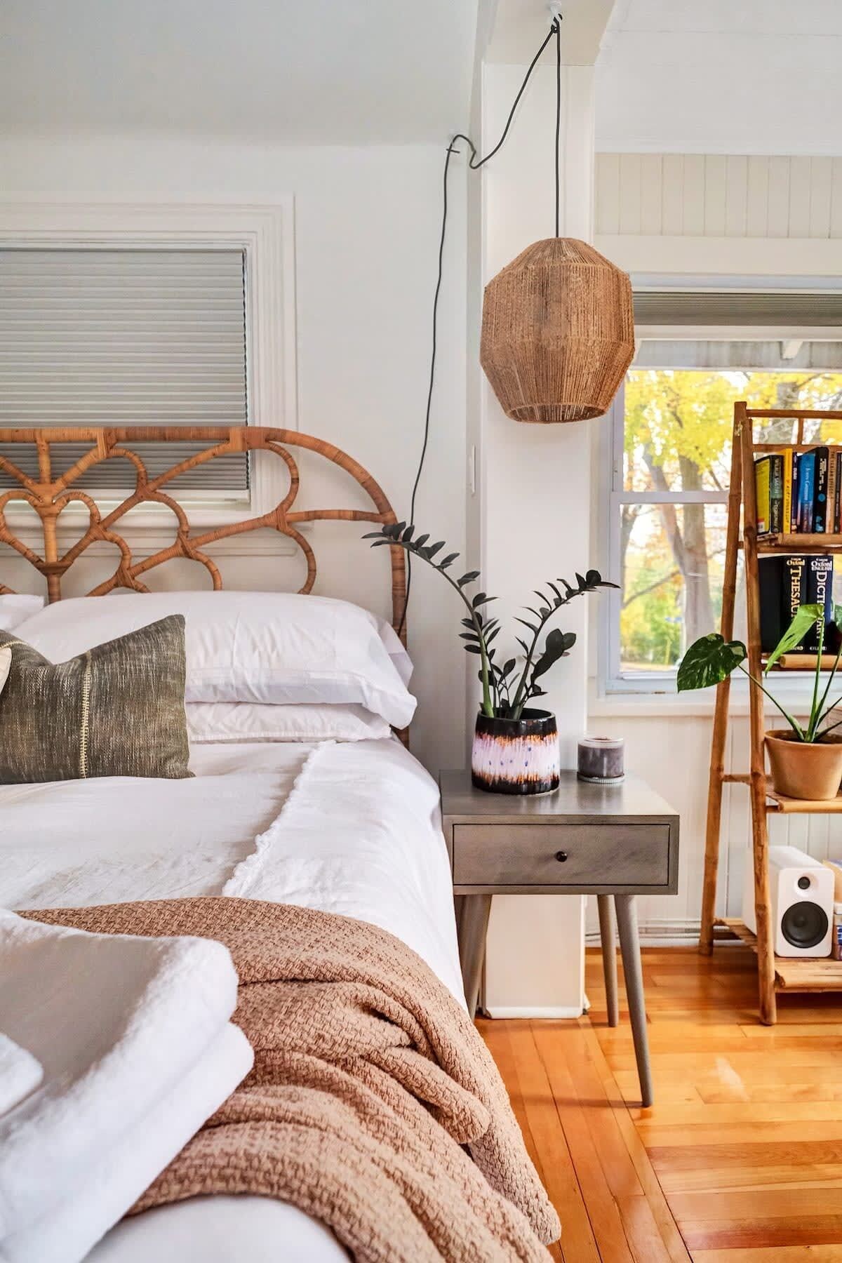 A bedroom with a bed, bedside table, lamp, and a bookshelf.