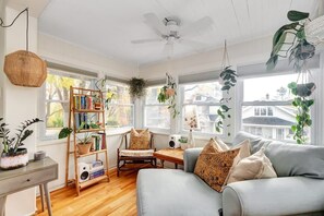 A cozy living room with a sofa, a wooden bookshelf, and hanging plants.