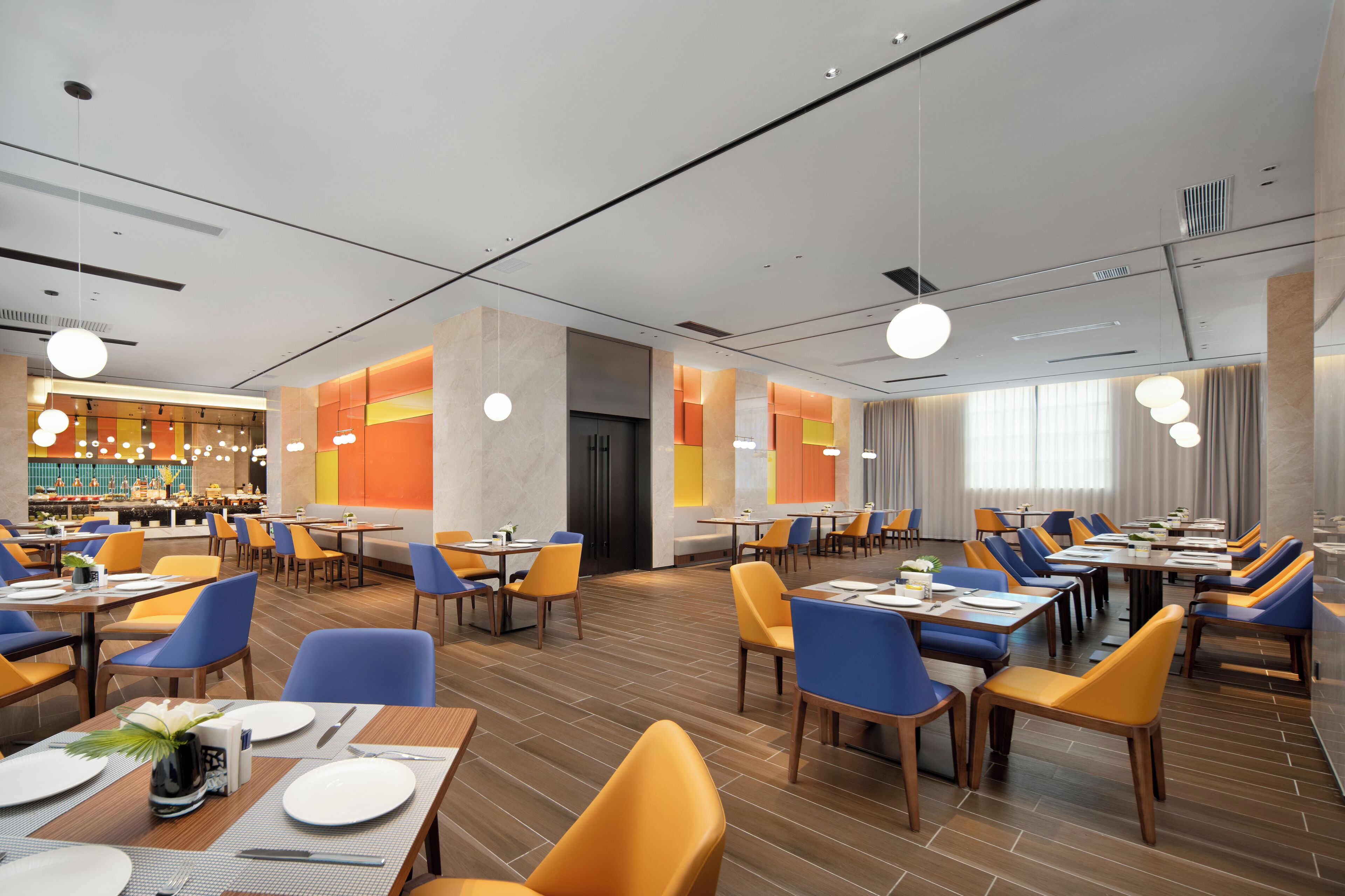 Een moderne eetruimte met meerdere tafels en stoelen, een bar en een groot raam met gordijnen.