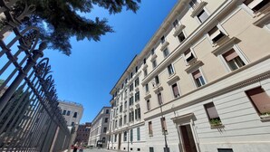 A street with a row of classical buildings, a metal fence, and a clear blue sky. - Luxury home in the Ghetto's heart (Roma)