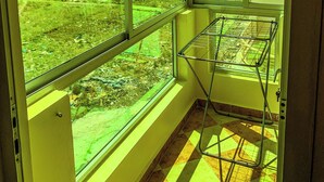 A room with large windows, a metal drying rack, and a view of a residential area. - Appartement Meublé à Tanger, Parfait Pour les Familles (Tanger)