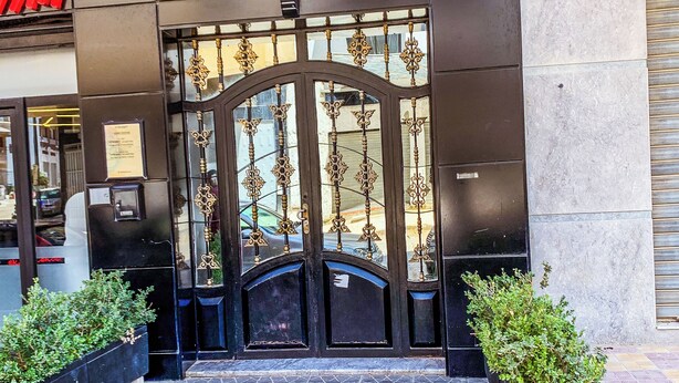 A building entrance with a metal gate, tiled pavement, and potted plants. - Appartement Meublé à Tanger, Parfait Pour les Familles (Tanger)