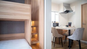 Een moderne kamer met een stapelbed, een kitchenette en een eethoek met stoelen.