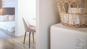 Een moderne hotelkamer met een stapelbed, een stoel en een wasmachine.