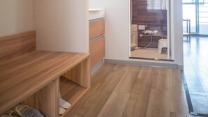 Een moderne badkamer met een houten wastafelmeubel, een bankje en een douchegedeelte.