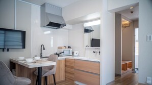 Een moderne keuken met een eethoek, houten kastjes, een magnetron en een flatscreen televisie.