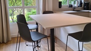 Una cocina moderna con un ventanal grande, una mesa de comedor y dos sillas.