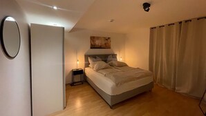 Un dormitorio con cama, mesitas de noche, una obra de arte en la pared y una lámpara en el techo.