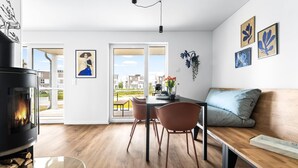 A modern living room with a fireplace, a dining area with a table and chairs, a sofa, and a view of the outside. - Pet friendly apartment in Olpenitz (Olpenitz)