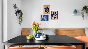 A dining area with a black table, orange chairs, a wooden bench, and a blue vase on a white shelf. - Pet friendly apartment in Olpenitz (Olpenitz)