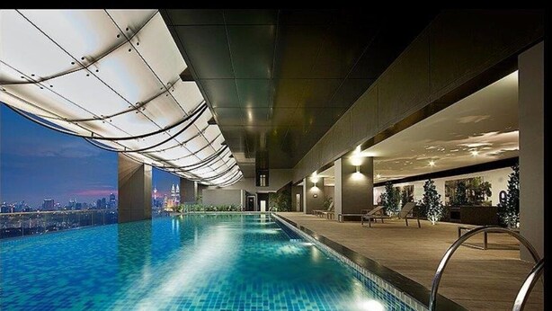 An indoor swimming pool with a city view, a covered walkway, and lounge seating. - M city ampang KL by Rit (Kuala Lumpur)