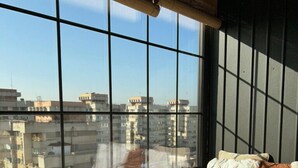 A room with a large window, a bed with pillows, and a view of a cityscape. - Exodus - Iasi City Center (Iași)