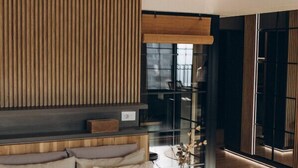Ein modernes Schlafzimmer mit einem großen Bett, einer Wand aus Holzlamellen und einer Glastür, die auf einen Balkon führt.