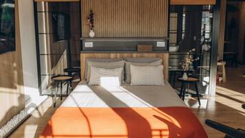 A modern bedroom with a large bed, a wooden headboard, and a small table with a vase.