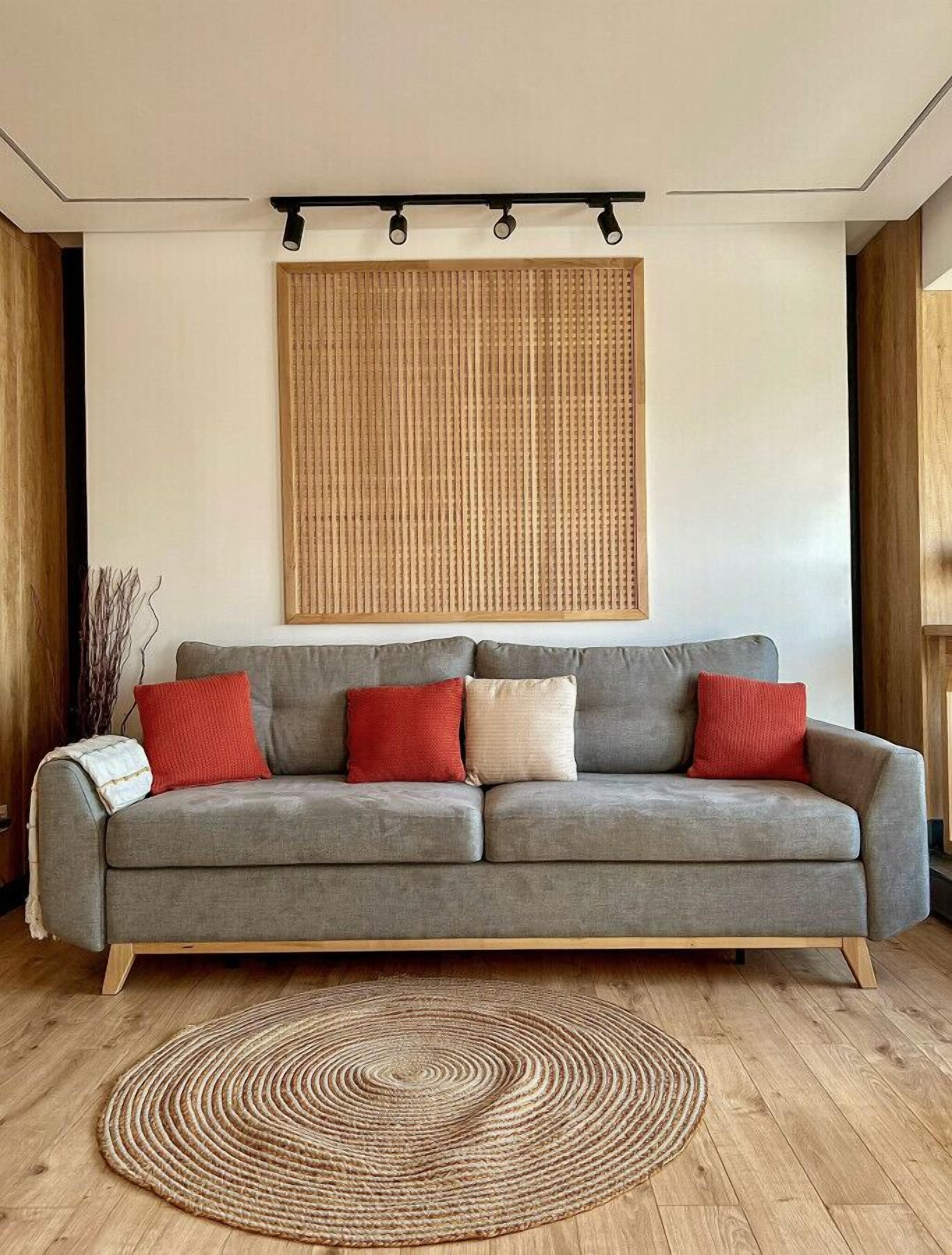 Una sala moderna con un sofá gris, un tapiz tejido y un rug circular.