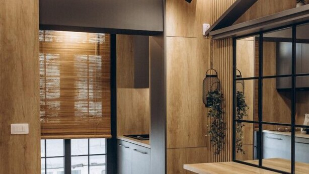 Eine moderne Küche mit Holzschränken, einer integrierten Bank und einem Fenster mit Jalousien.