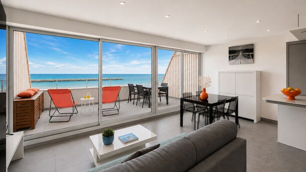 A modern living room with a sofa, coffee table, and dining area, featuring a large sliding glass door to a balcony with a view of the sea. - Rose des Sables • A Terrace Over the Mediterranean (Mauguio)