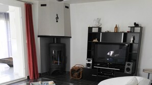 A modern living room with a white leather sofa, a glass coffee table, a fireplace, a black entertainment unit, and a red curtain. - Maison Castellane (Castellane)