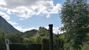 A garden with a metal grill, a black pole, and a stone pathway. - Maison Castellane (Castellane)