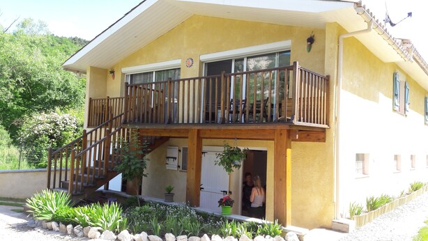 A two-story building with a balcony, a staircase, and a garden area with plants and rocks. - Maison Castellane (Castellane)