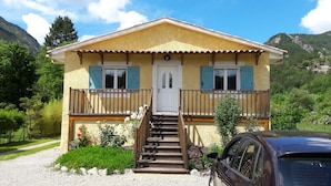 A two-story house with a front porch, a staircase leading to the entrance, and a car parked in front. - Maison Castellane (Castellane)
