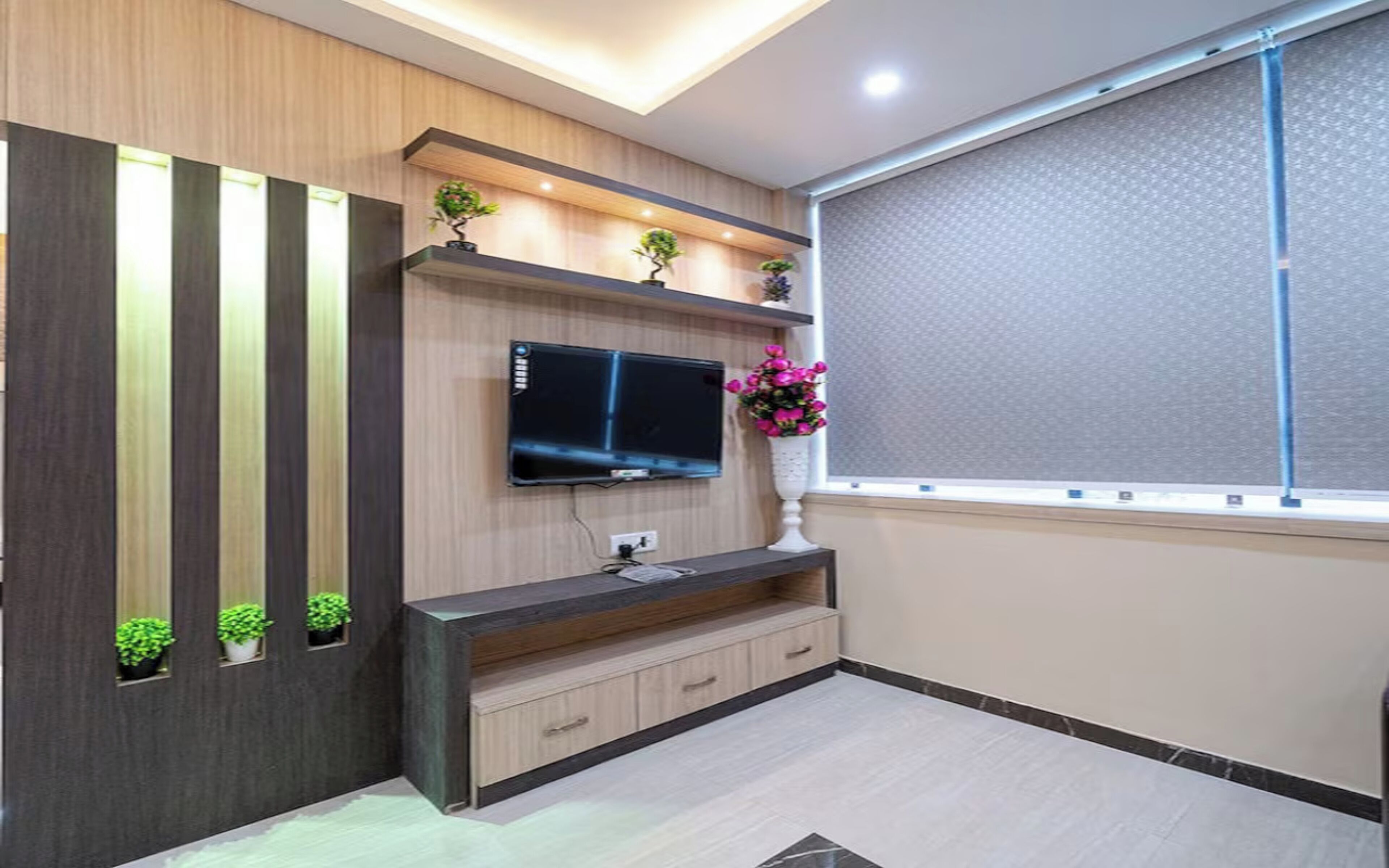 Una sala de estar moderna con televisor empotrado, pared de paneles de madera y ventana con vistas.