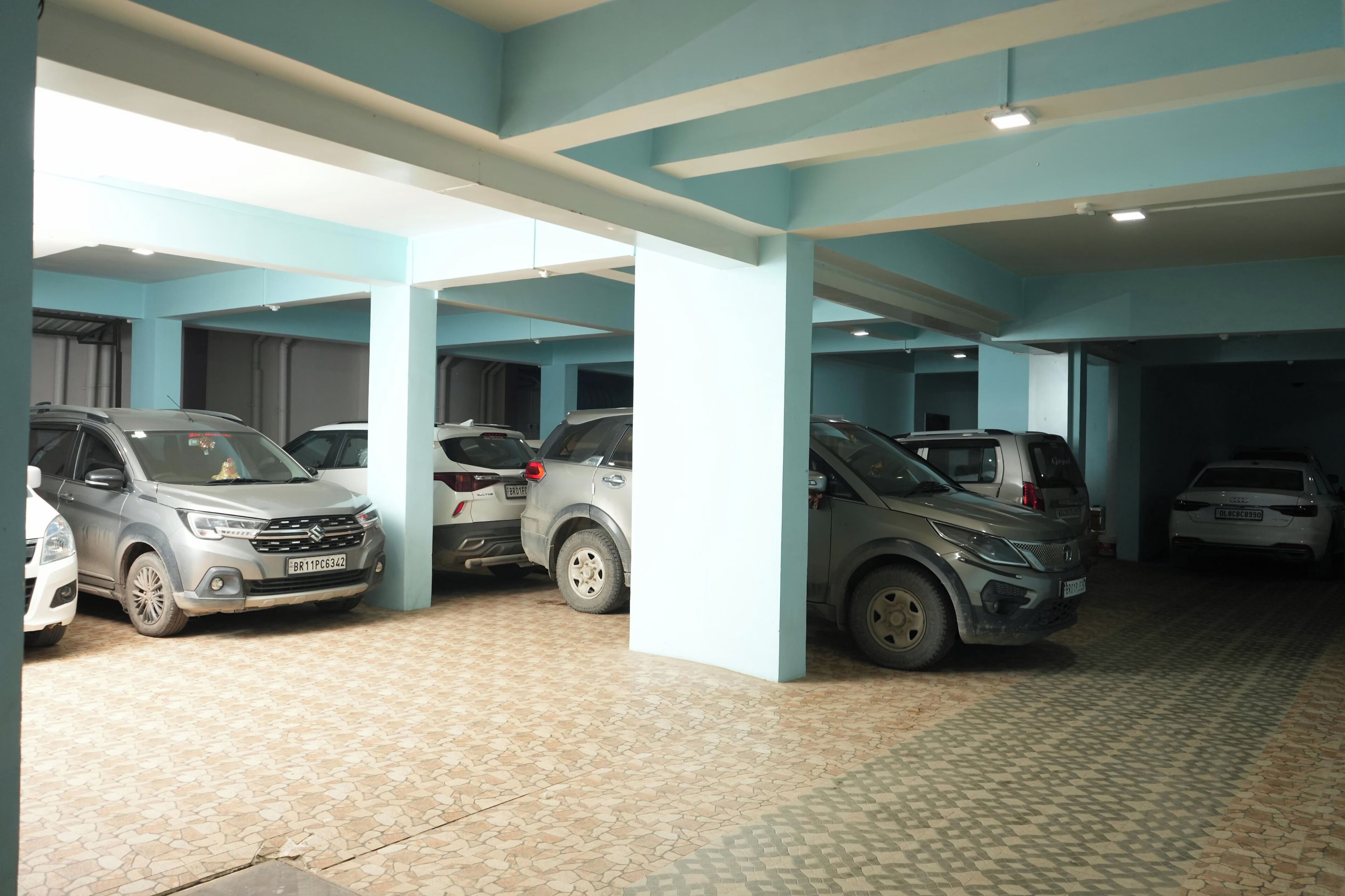 A parking garage with multiple cars parked under blue and white pillars.