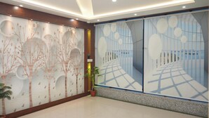 A modern lobby with a tree mural, a potted plant, and a view corridor. - Hotel Holiday Saharsa (Saharsa)