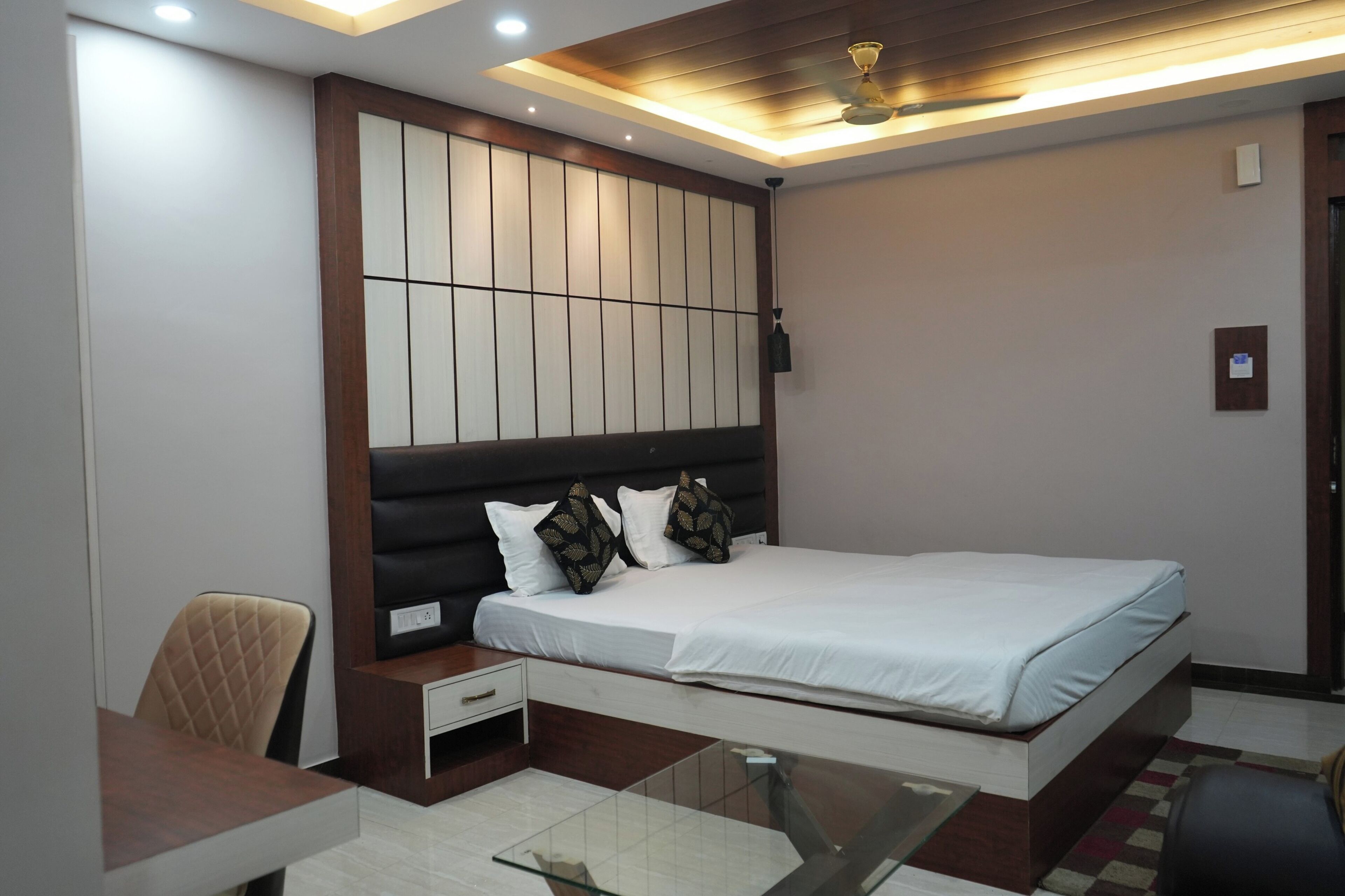 A modern bedroom with a large bed, a desk, and a chair.