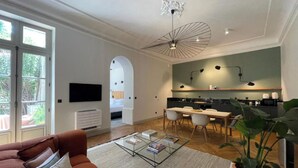 A modern living room with a sofa, coffee table, and a dining area with chairs and a table. - Le Jardin des Etudes - Terrace & Mansion 300 Years (Avignon)