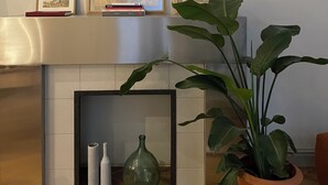 A living room with a fireplace, framed artwork on the mantel, a potted plant, and decorative vases. - Le Jardin des Etudes - Terrace & Mansion 300 Years (Avignon)