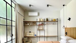 A hotel room with a bed, a chair, a desk, and a shelf with decorative items. - Le Jardin des Etudes - Terrace & Mansion 300 Years (Avignon)