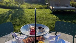 An outdoor dining setup with a table set for a meal, including plates of food, a drink, and a basket of bread. - Michlhaus nature and suites (Aldino)
