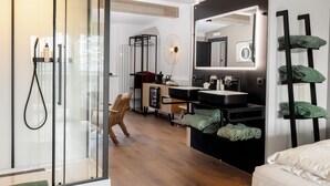 A modern bathroom with a glass shower enclosure, a large mirror, and a black vanity with a sink and countertop. - Michlhaus nature and suites (Aldino)