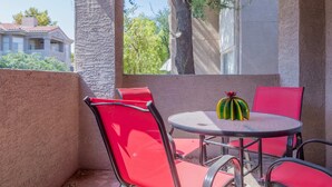 A patio with red chairs and a table, a tree, and a building in the background. - Modern Retreat in Ahwatukee, Heated Pool, Spa, Gym (Phoenix)