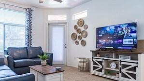 A living room with a TV, a sofa, a coffee table, and decorative wall art. - Modern Retreat in Ahwatukee, Heated Pool, Spa, Gym (Phoenix)