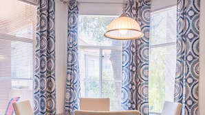 A dining area with a round table and four chairs, patterned curtains, and a hanging light fixture. - Modern Retreat in Ahwatukee, Heated Pool, Spa, Gym (Phoenix)