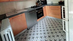 A compact kitchen with wooden cabinets, a gas stove, a built-in oven, and a white refrigerator. - Quiet house between Disneyland and Paris (Villiers-sur-Marne)