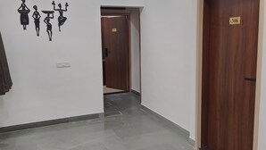 A hallway with a ceiling fan, a wall-mounted light fixture, and a door with a number plate.