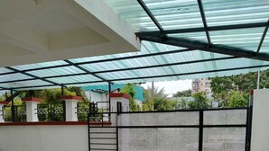 A covered outdoor area with a tiled floor, a metal gate, and a white wall with a decorative pattern.