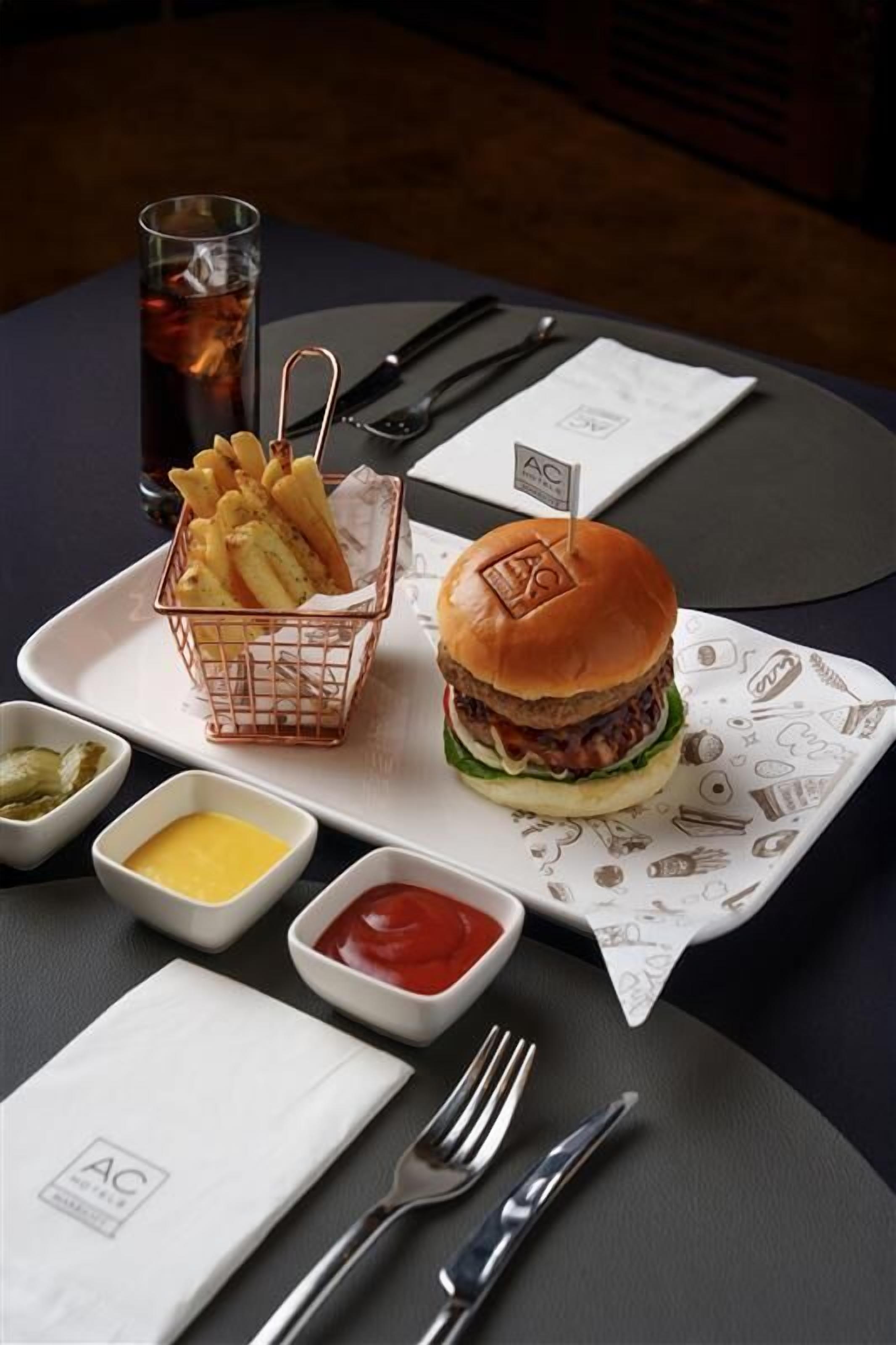 Un plateau repas contenant un hamburger, des frites et des condiments, posé sur une table.