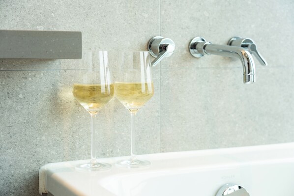 Un baño con una bañera, dos copas de vino en la pared y un perchero para toallas.