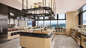A modern kitchen with a central island, multiple serving stations, and large windows offering city views.